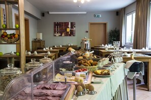 Un buffet proposant une variété de plats, un coin café et une présentation de fruits.