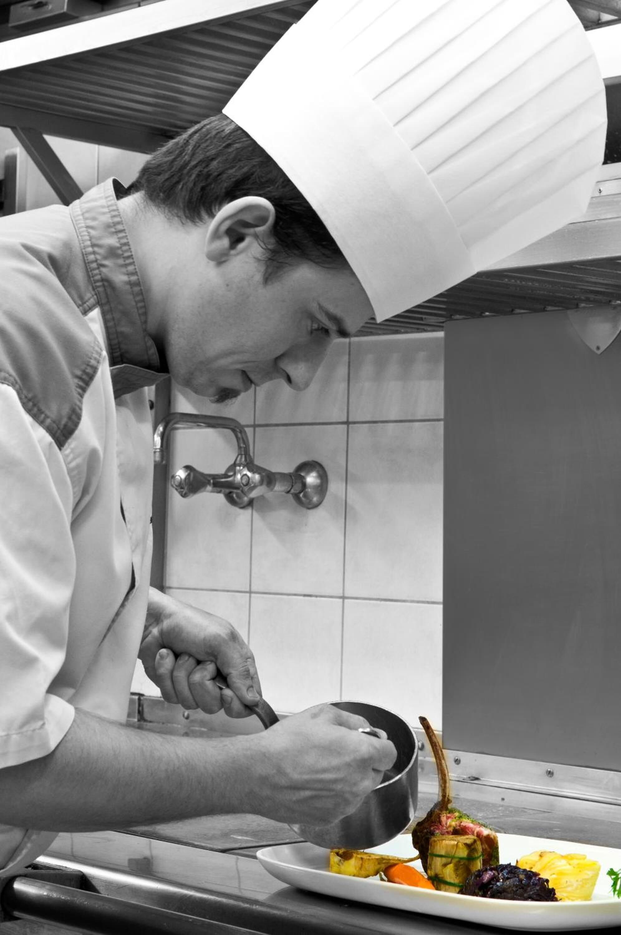 A chef in a professional kitchen, preparing food.