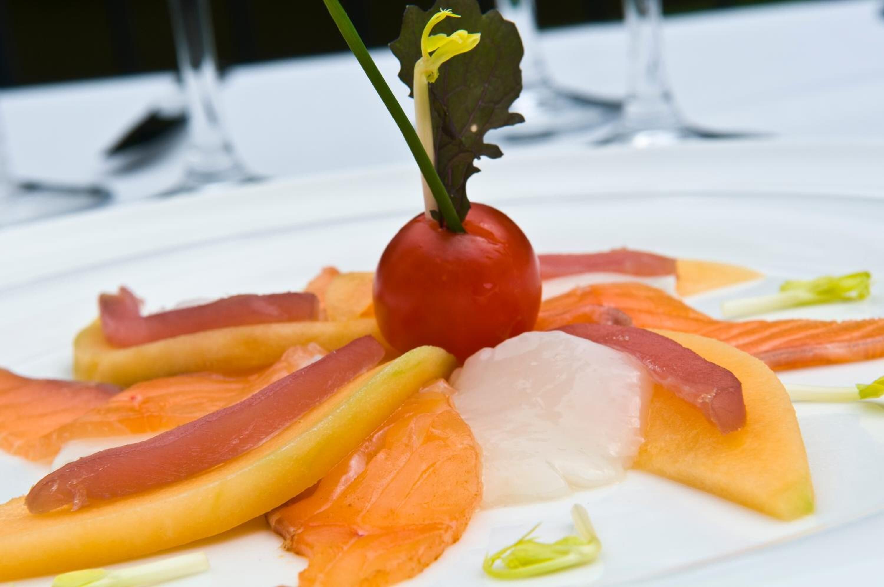 A plate of food with salmon, vegetables, and a cherry tomato garnish.
