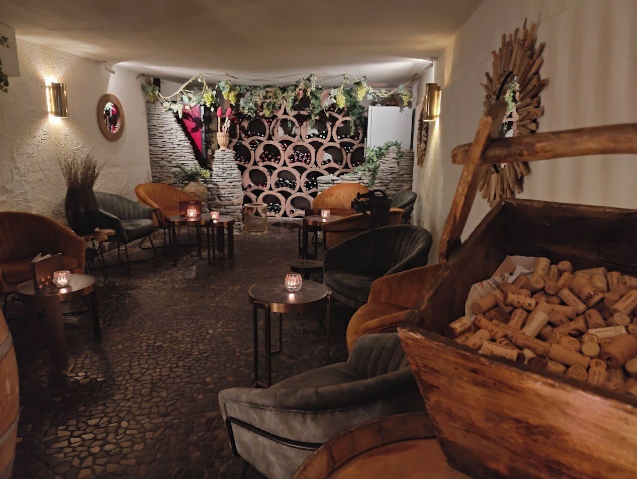 Ein gemütliches, rustikales Interieur mit Steinwänden, Holzmöbeln und einem Fass voller Weinkorken.
