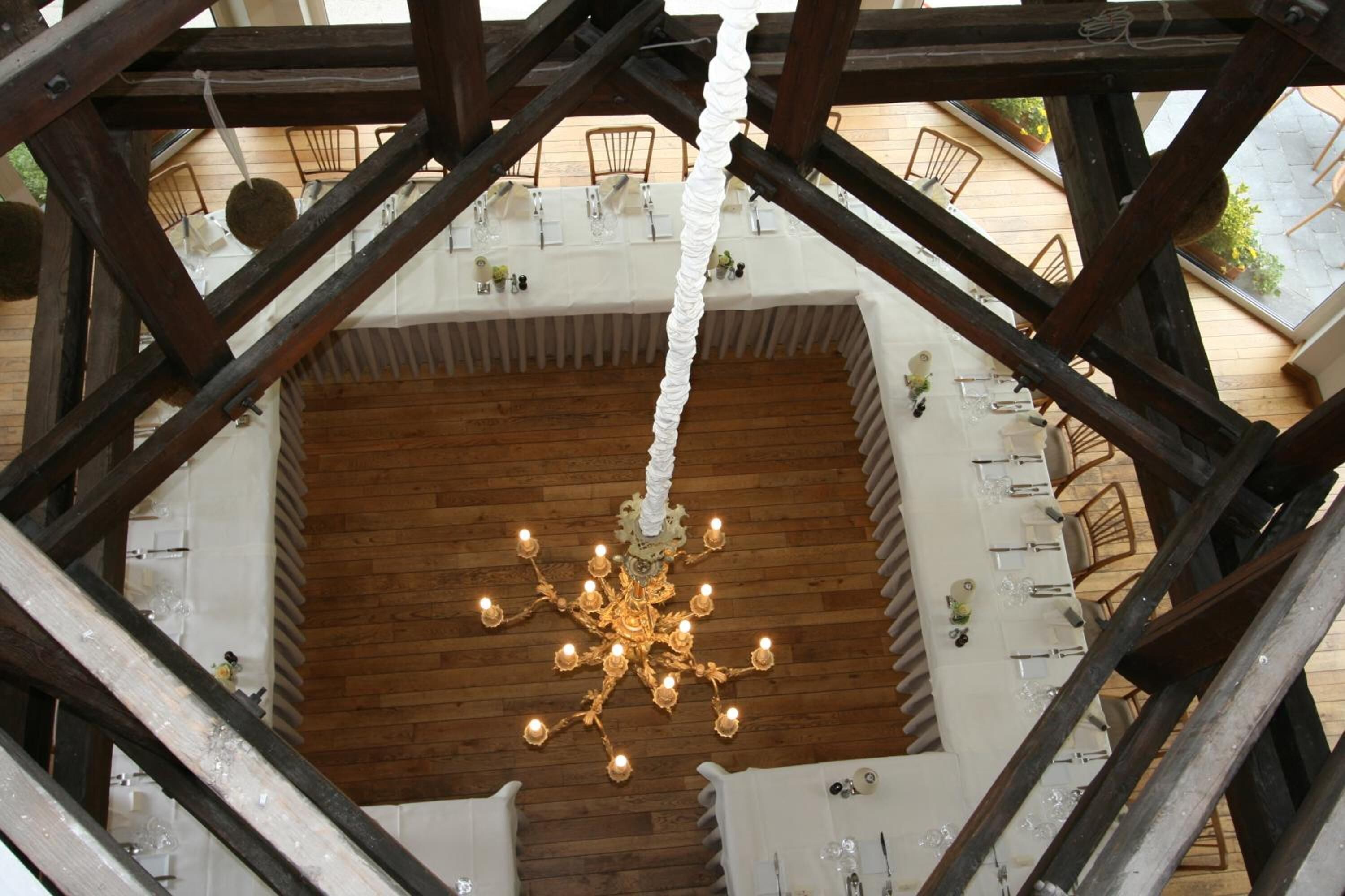 Un comedor de madera con techos altos, con una araña colgante, rodeado por una estructura de madera con vigas a la vista.