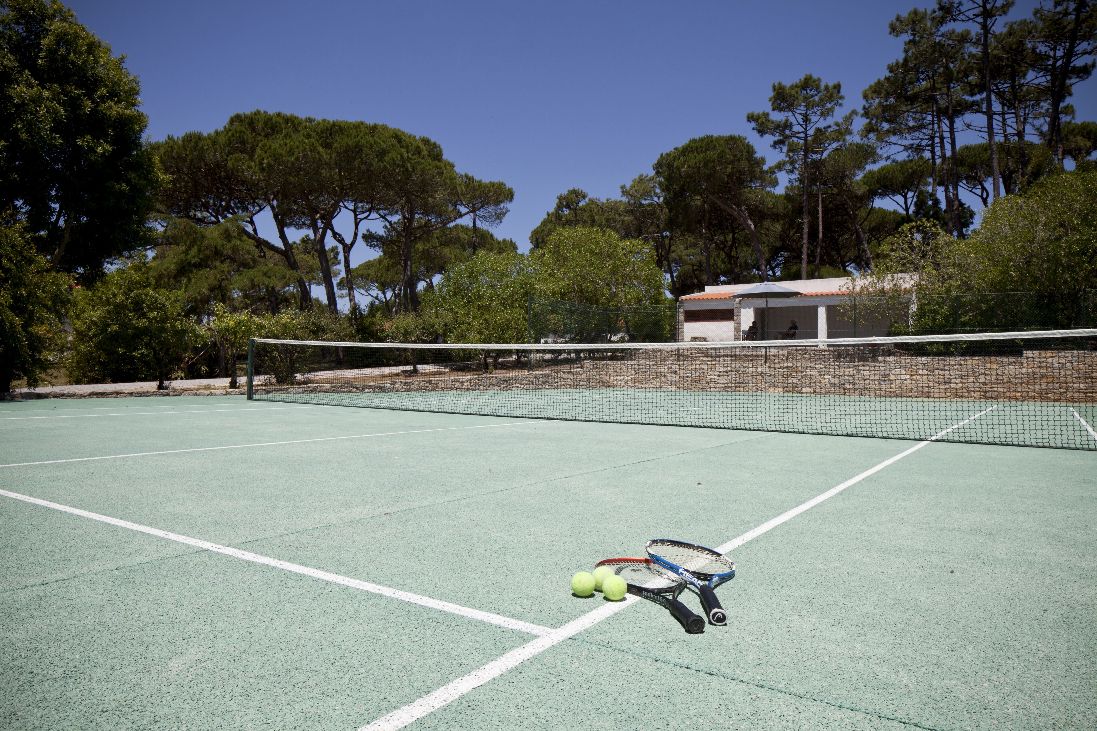 A tennis court with a net, tennis rackets, and balls.