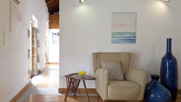 Una sala de estar con un sofá color beige, una pequeña mesita de madera con un jarrón y un cuadro en la pared.