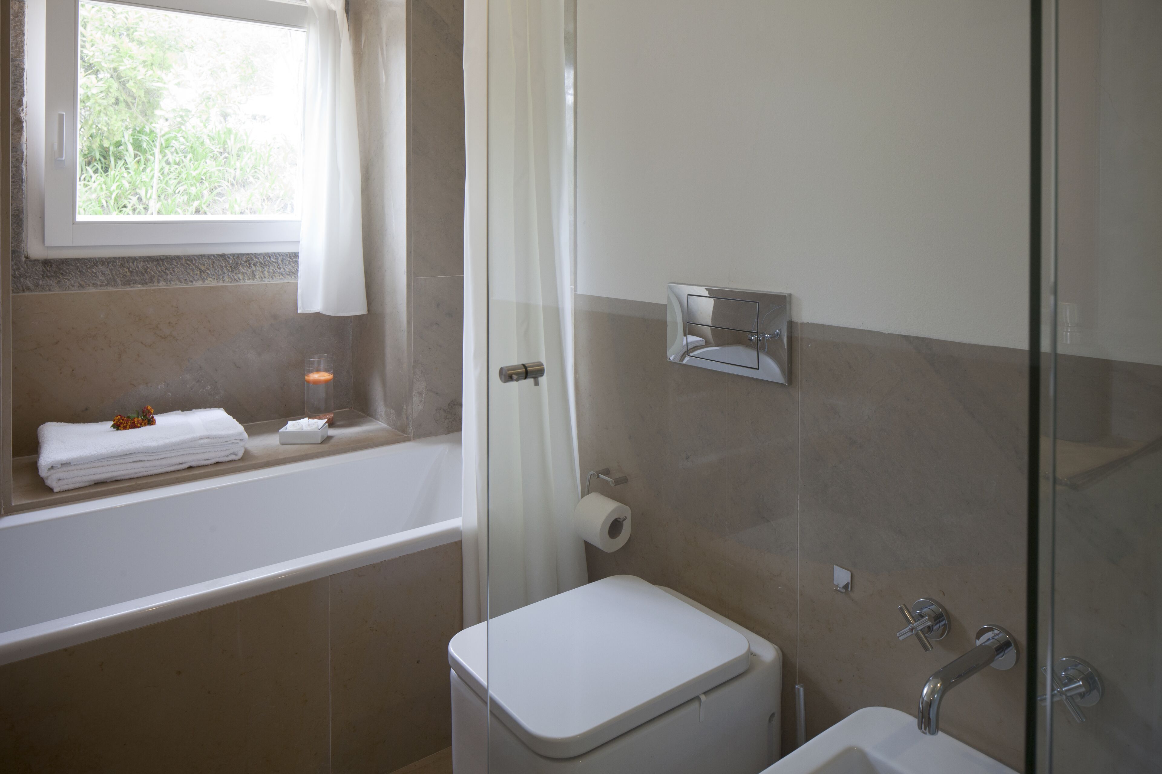 Een badkamer met een bad, toilet en douche.