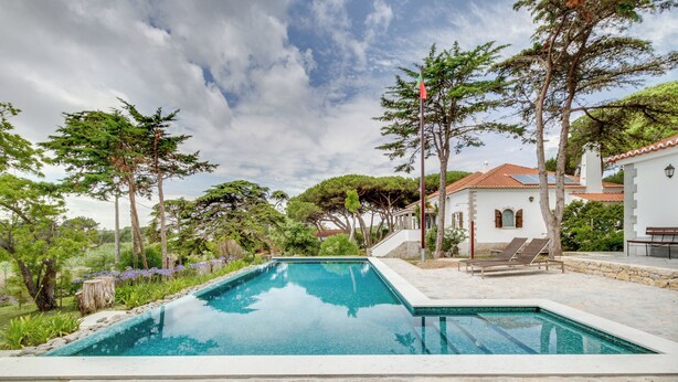 A rectangular swimming pool with a stone border, surrounded by trees and a white building with a red roof. - Solar do Magoito (Sintra)