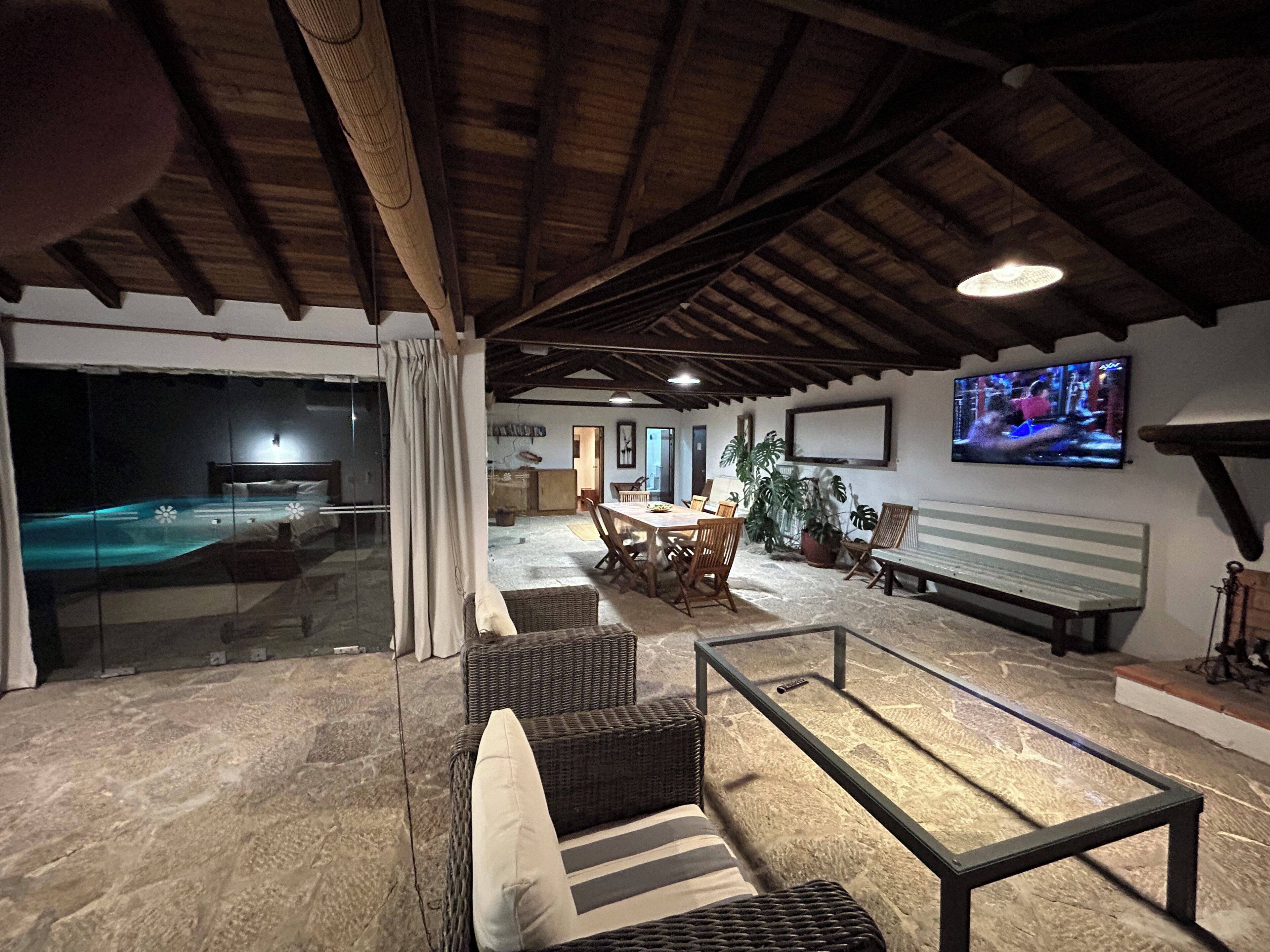 Um quarto espaçoso com piscina, área de jantar e televisão.