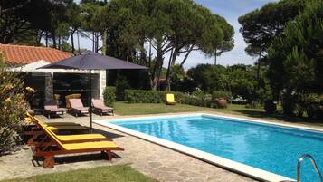 Una piscina al aire libre, sombrillas, sillones reclinables de piscina