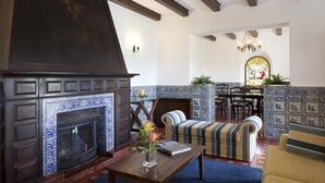 A living room with a fireplace, striped sofa, and a dining area with a stained glass window. - Solar do Magoito (Sintra)