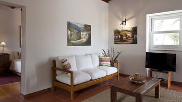 A living room with a white sofa, wooden coffee table, and paintings on the wall.