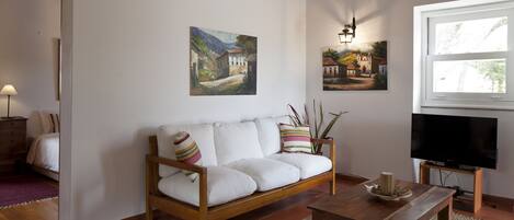 Un salon avec un canapé blanc, une table basse en bois et des tableaux accrochés au mur.