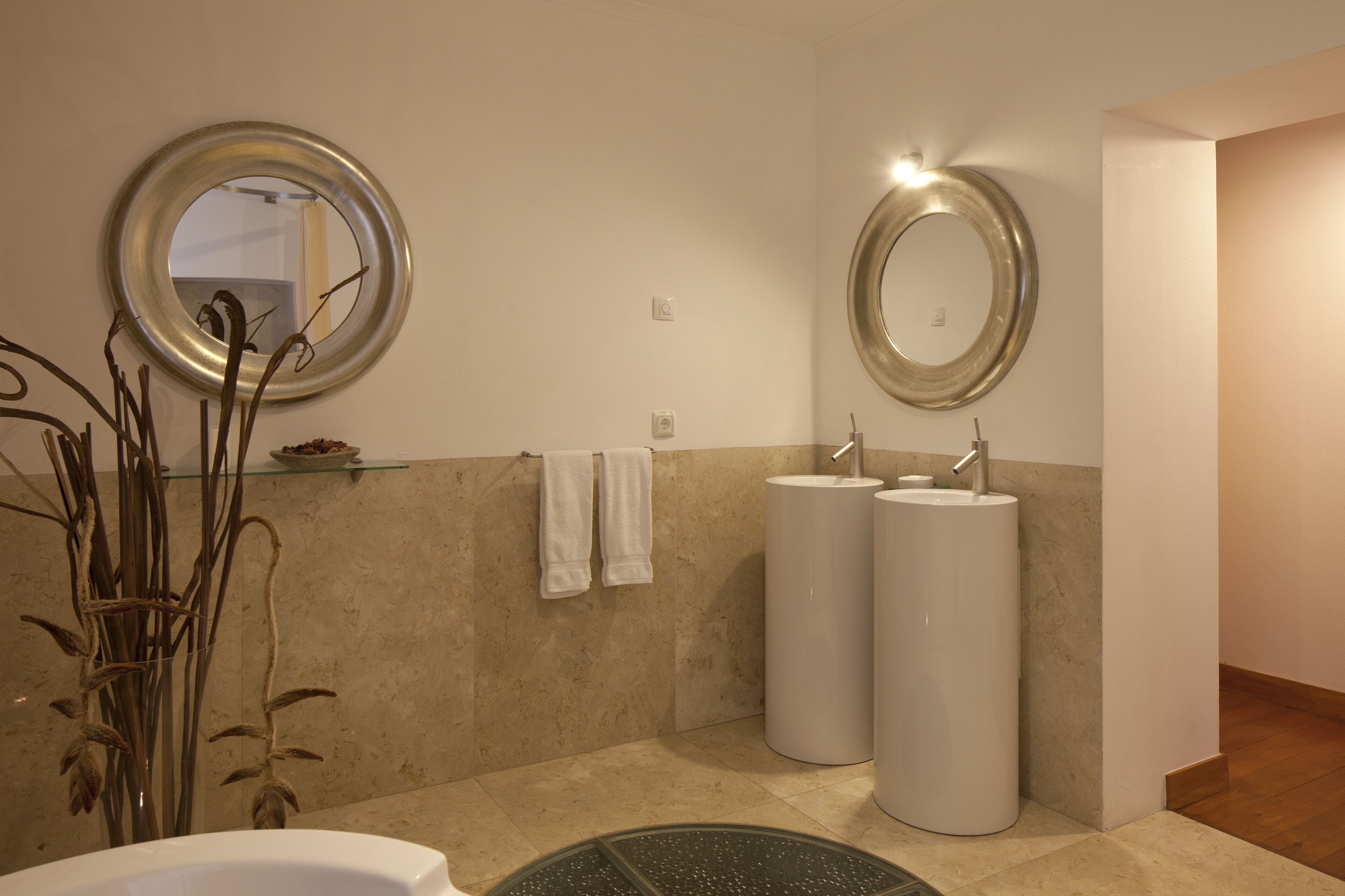 Un baño moderno con dos lavamanos, un espejo grande y una planta decorativa.