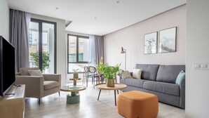 A modern living room with a sofa, armchair, coffee table, and ottoman. -  Limehome Barcelona Rector Triadó (Barcelona)