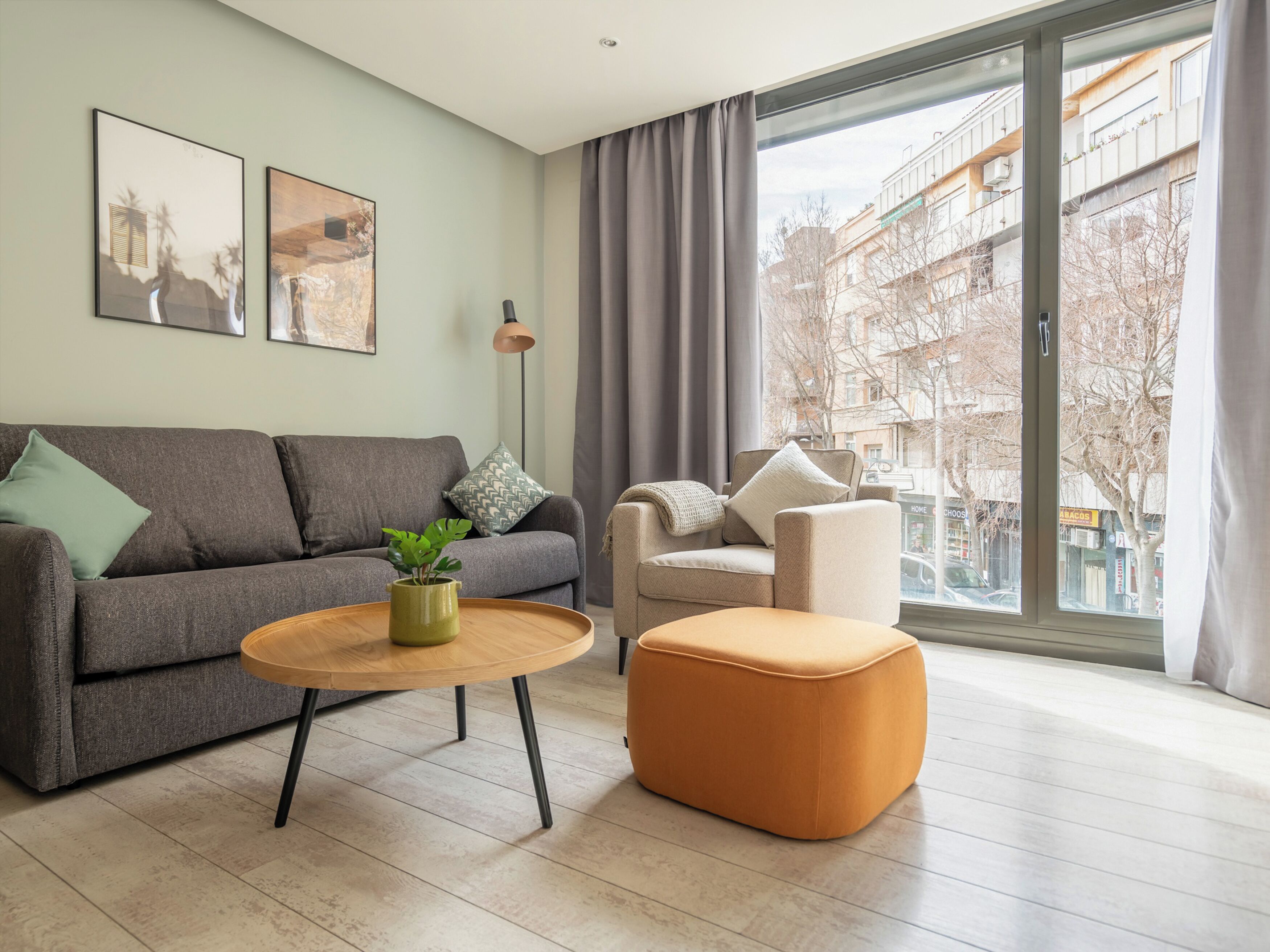 A modern living room with a grey sofa, a round wooden coffee table, and a beige armchair.