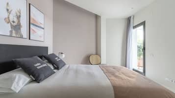 Un dormitorio moderno con una cama grande, dos almohadas, una mesita de noche, una lámpara y vistas al exterior.