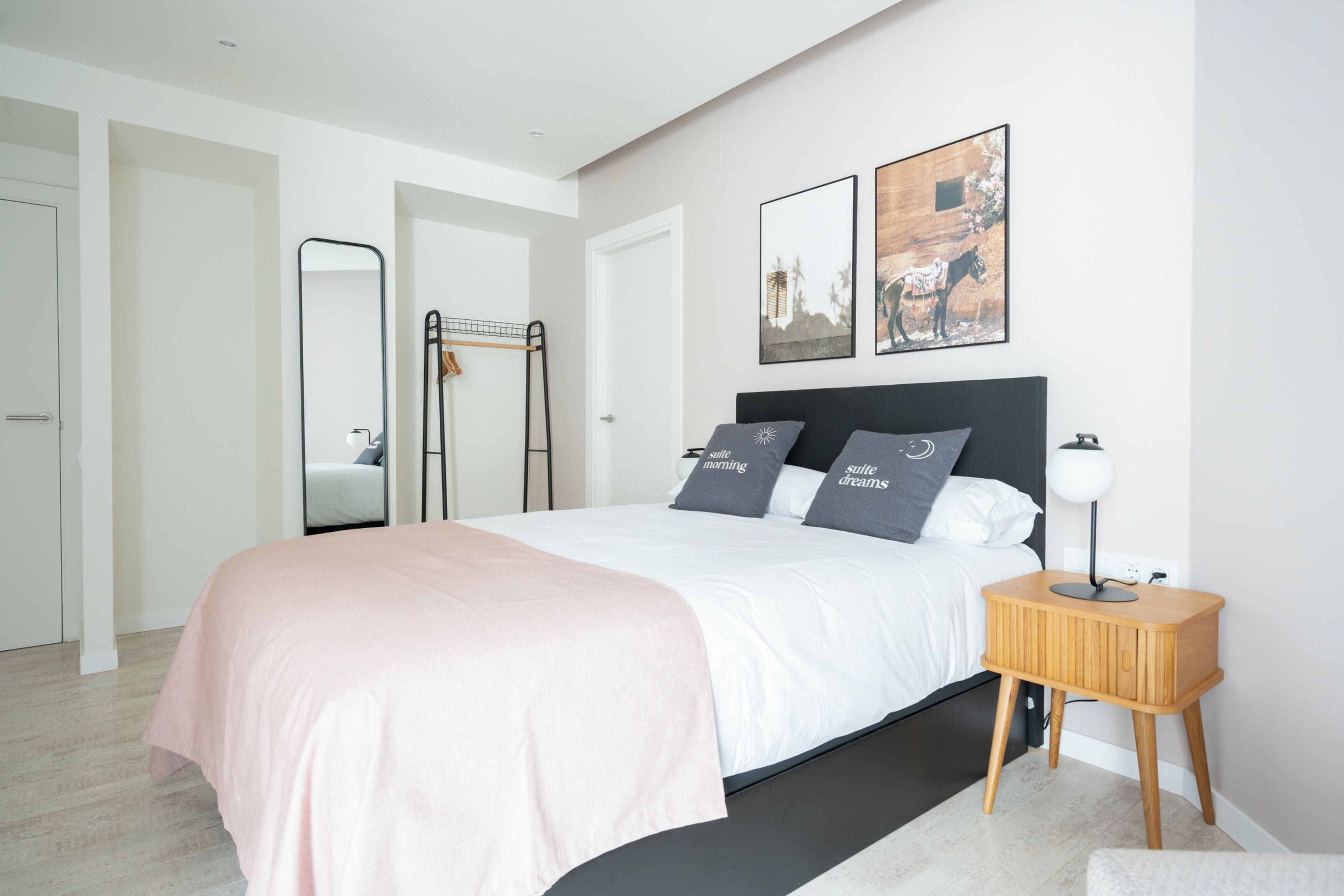 A modern bedroom with a bed, bedside table, and artwork on the wall.