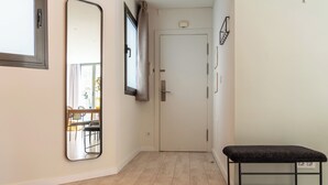 A hallway with a bench, a door, a mirror, and a window with curtains. -  Limehome Barcelona Rector Triadó (Barcelona)