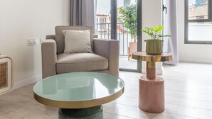 A modern living room with a round glass table, a beige armchair, a small round table with a plant, and a view of the outside through large windows. -  Limehome Barcelona Rector Triadó (Barcelona)