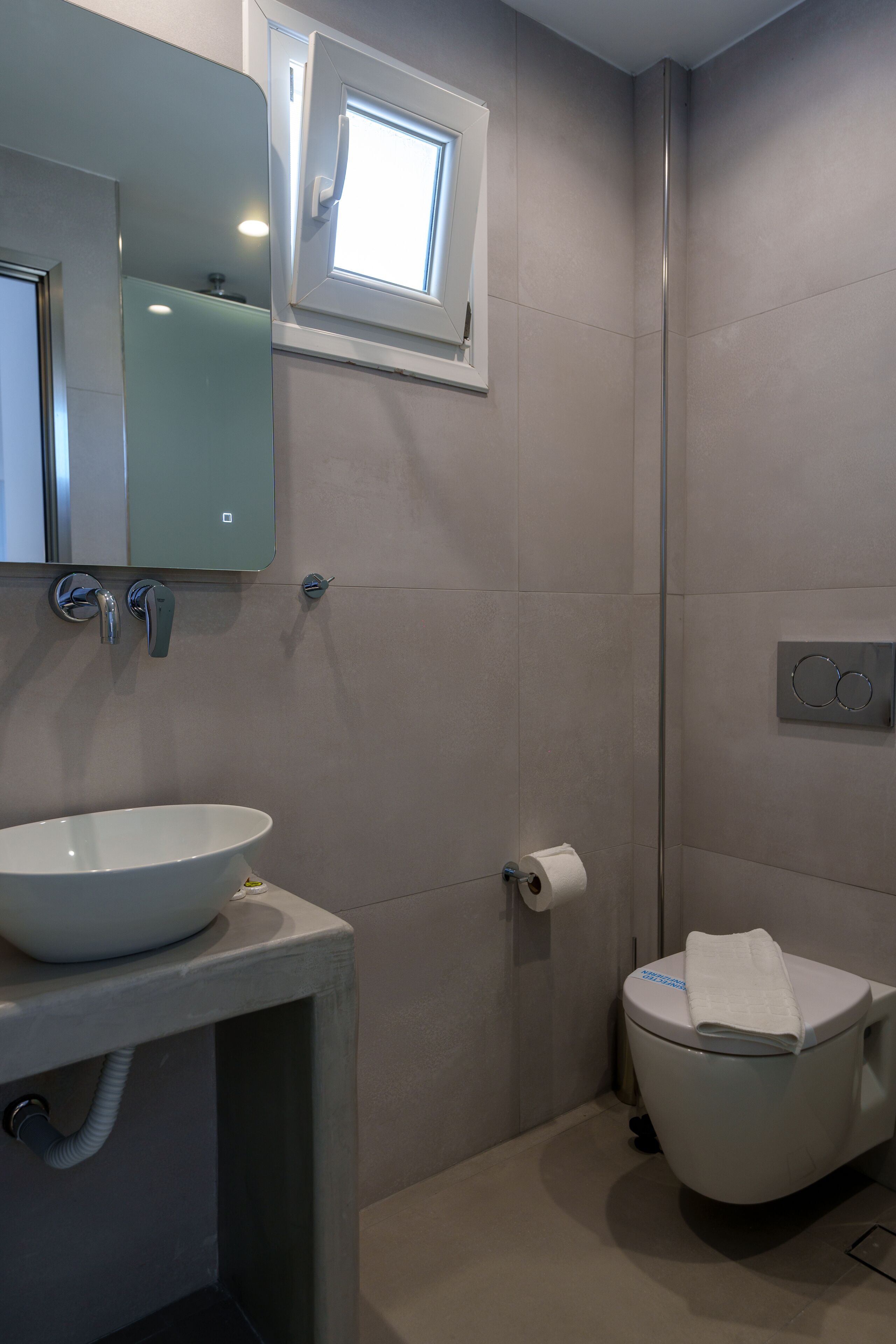 Ein Badezimmer mit Waschbecken, Spiegel, Toilette und Fenster.