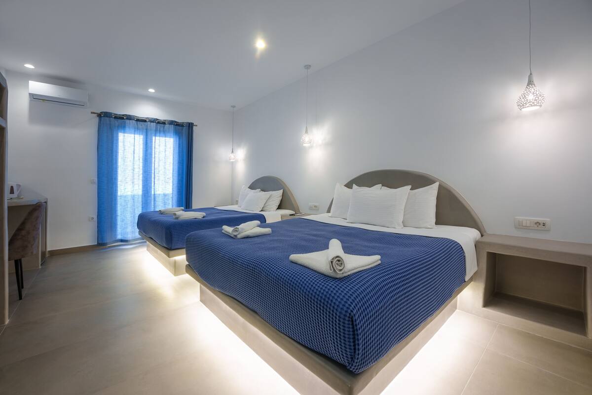 Una habitación de hotel moderna con dos camas, un escritorio y una zona de ducha.