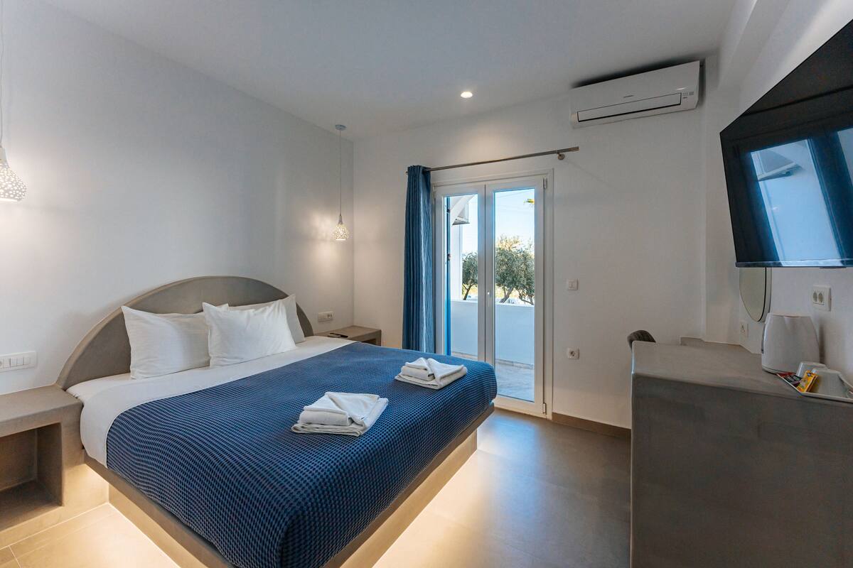 Una habitación de hotel moderna con una cama grande, un escritorio y un televisor.