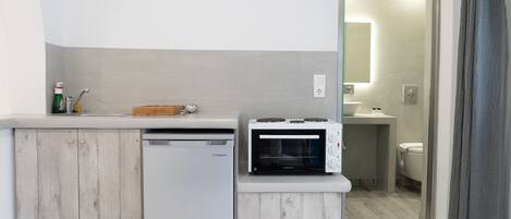 Una kitchenette compacta con lavavajillas, horno integrado y una pequeña encimera.