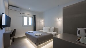 Una habitación de hotel moderna con cama, mesita de noche, televisor y ventana con cortinas.