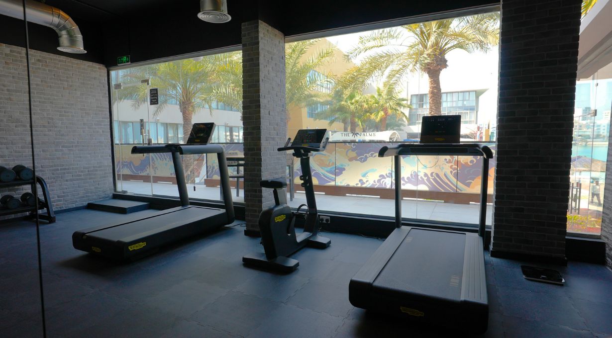 Un gimnasio con cintas de correr, una bicicleta estática y un banco para pesas.