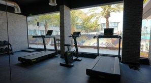 A gym with treadmills, a stationary bike, and a weight bench. - Dragon Beach Hotel (Amwaj Islands)
