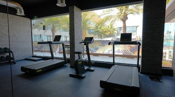 Ginásio com esteiras, bicicleta ergométrica e um banco de musculação.