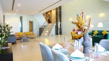 A modern living room with a dining area, a staircase, and a green sofa.