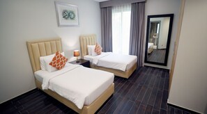 A hotel room with two beds, a large mirror, a nightstand, and a window with curtains. - Dragon Beach Hotel (Amwaj Islands)