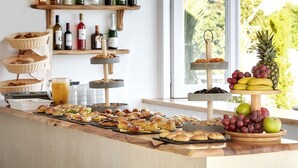 A buffet with various food items, a wine rack, and a fruit display. - Callia Retreat Adults Only (Santorini)