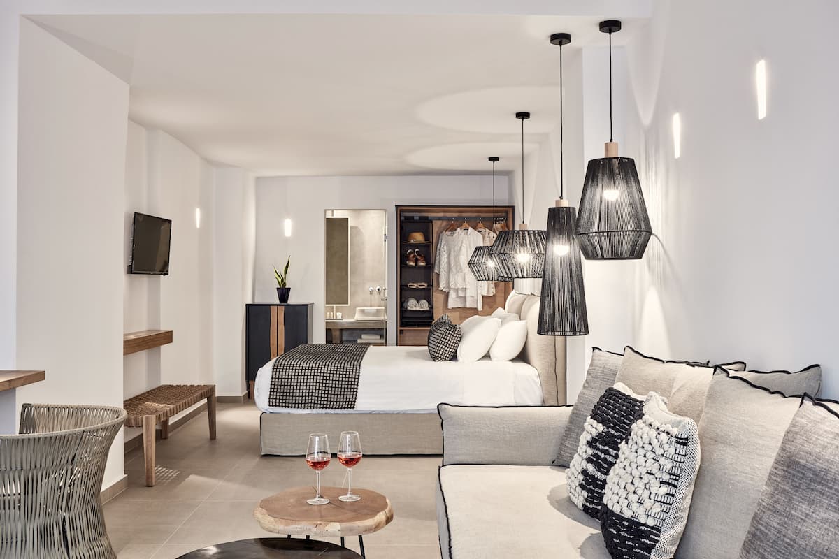 Ein modernes Hotelzimmer mit Bett, Sofa, Esstisch und Fernseher.