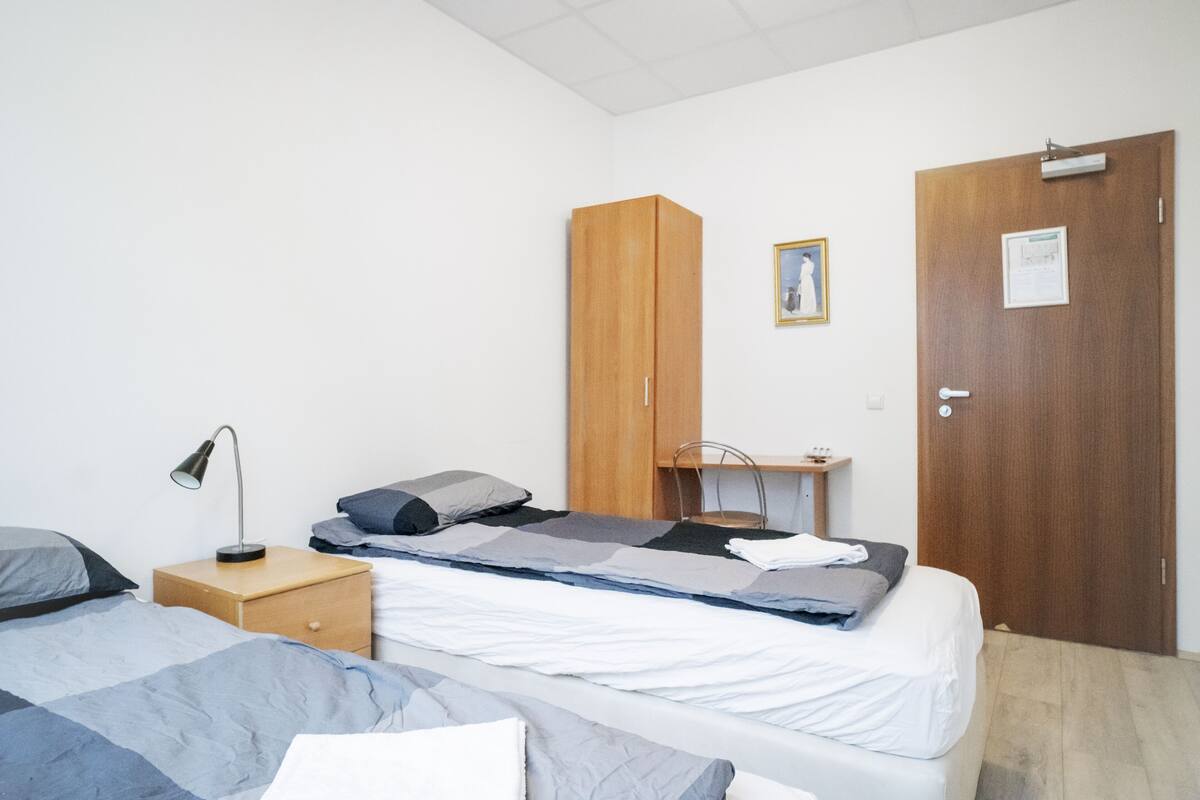 A bedroom with a bed, a nightstand, a wardrobe, and a door.