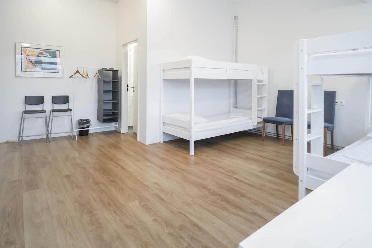A room with bunk beds, a desk, chairs, and a wardrobe.