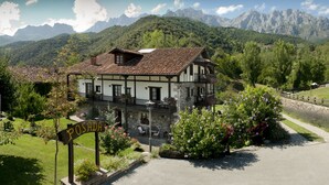 Un bâtiment traditionnel, avec une enseigne indiquant « POSADA », se dressant devant, entouré d’une végétation luxuriante et avec des montagnes en arrière-plan.