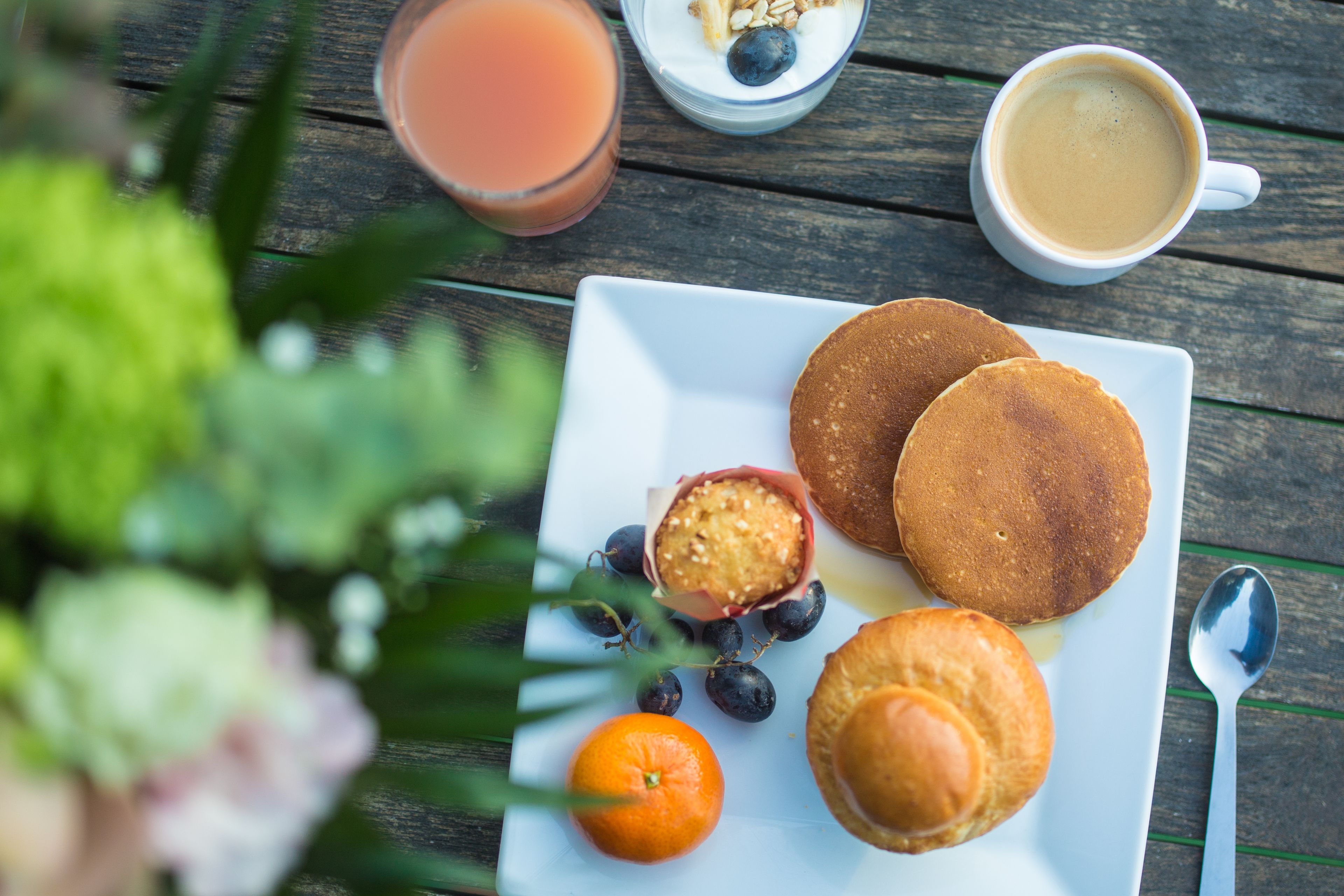 A breakfast plate with pancakes, a glass of orange juice, a cup of coffee, and a muffin with blueberries.