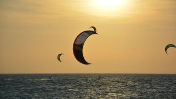 Un atardecer sobre un cuerpo de agua con varios kitesurfistas.