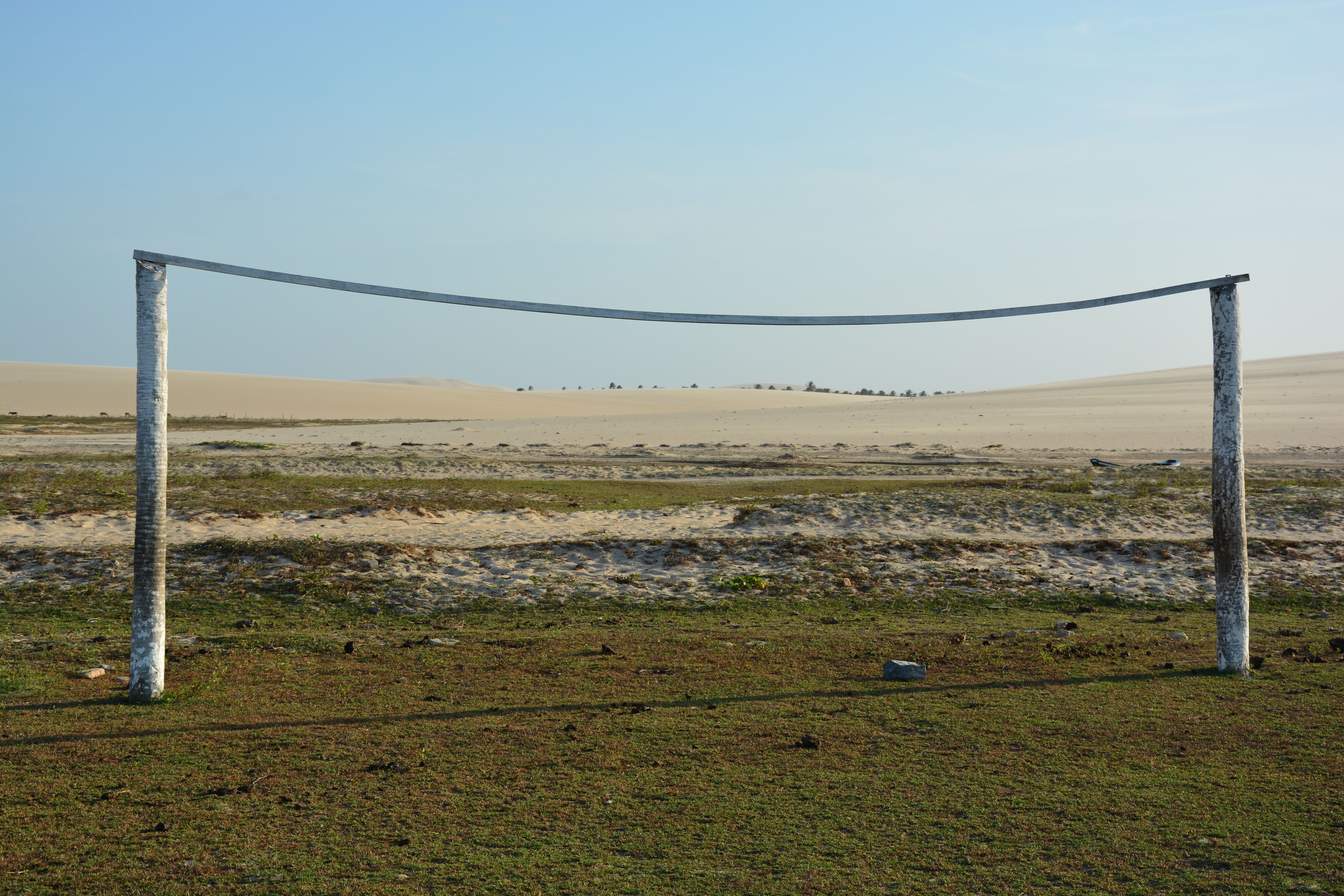 Paisaje desértico con una barrera de cuerda y vegetación escasa.