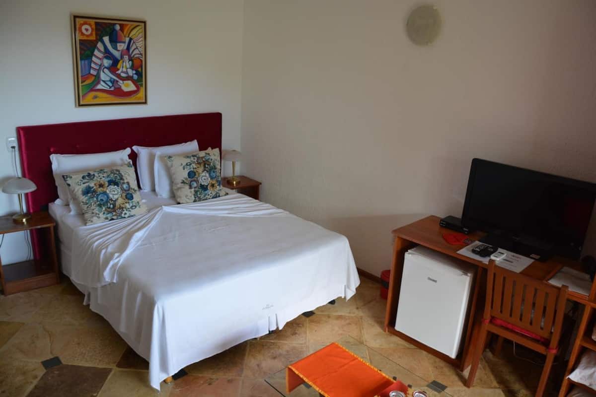Une chambre d’hôtel équipée d’un lit, d’une télévision, d’un petit réfrigérateur et d’un bureau avec une lampe.