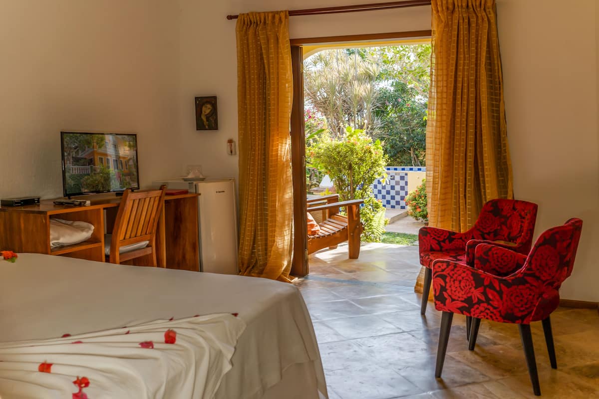 Une chambre d’hôtel avec un lit, un bureau, une télévision et une chaise rouge.