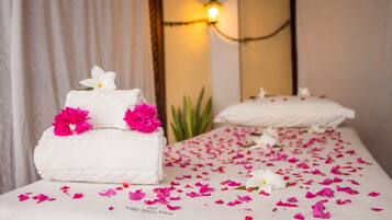 Relax in a serene spa treatment room with a long bed, white bedspread, and soft lighting.
