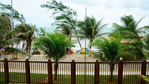 Un espace extérieur clos, agrémenté de palmiers et offrant une vue sur la plage.