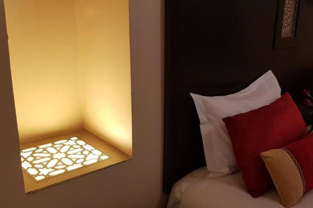 A hotel room with a bed, pillows, and a decorative wall panel.