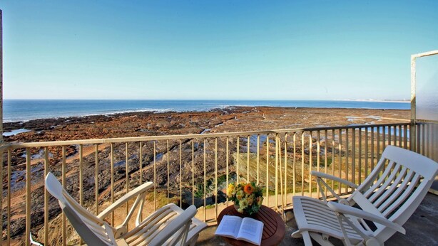A balcony with white chairs and a table, overlooking a rocky coastline and the sea. - Frederic (Saint-Hilaire-de-Riez)