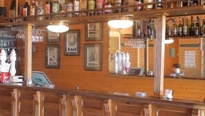 A bar area with wooden cabinets and shelves stocked with various liquor bottles. - Frederic (Saint-Hilaire-de-Riez)
