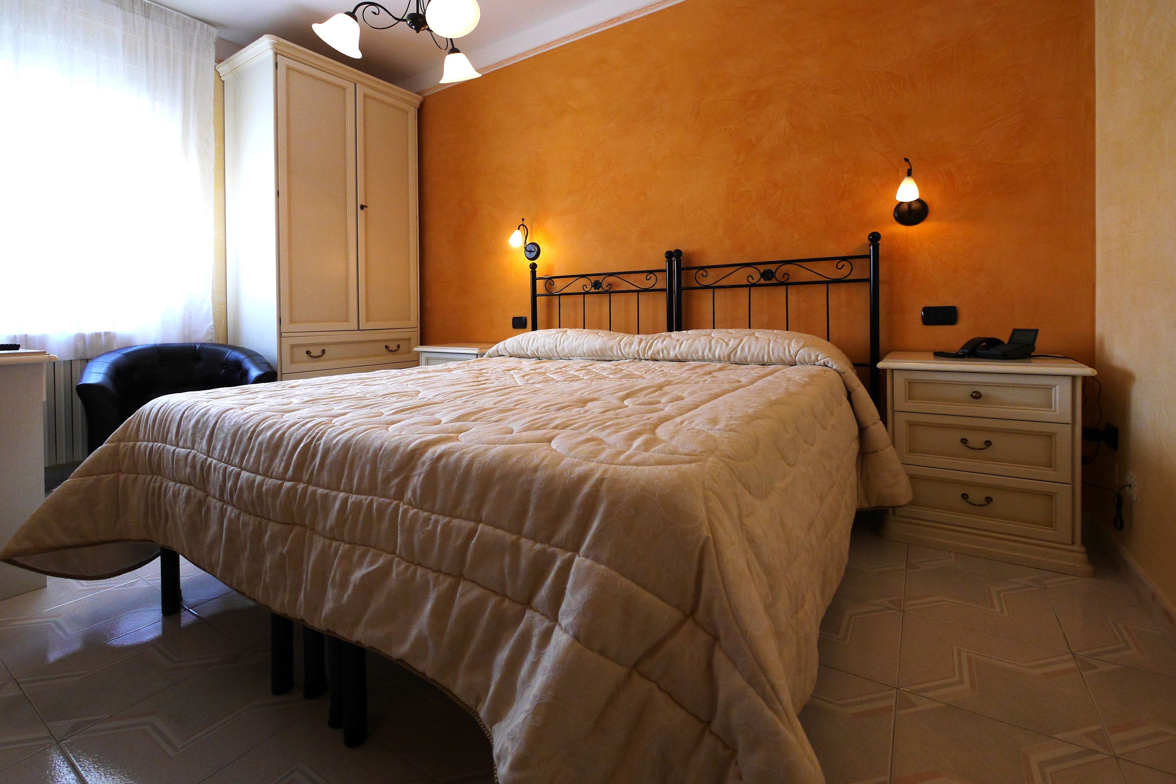 Una camera da letto con un letto, un armadio, un comodino e una lampada.