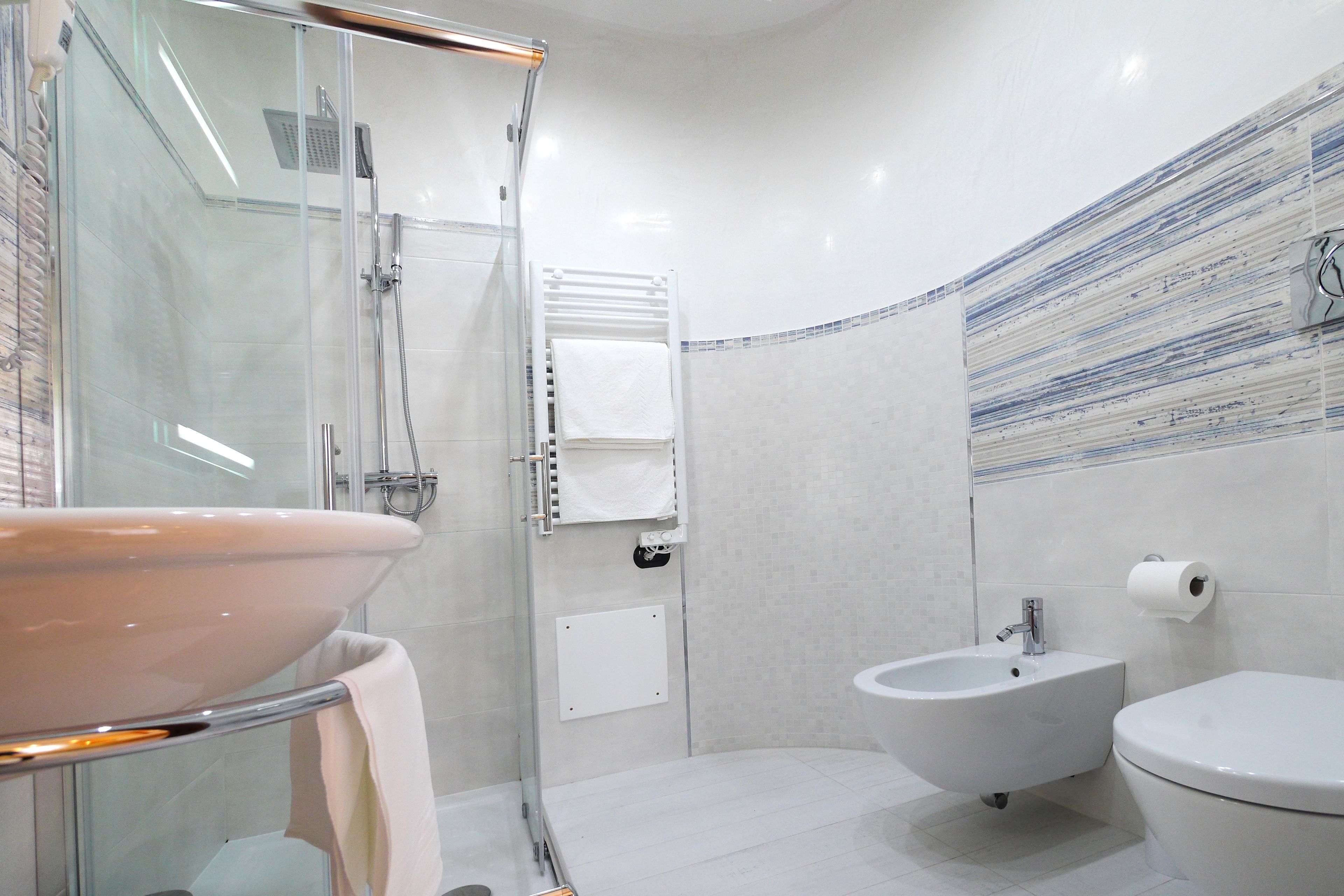 Une salle de bain moderne avec une douche à parois de verre, un lavabo blanc, un bidet et des toilettes.