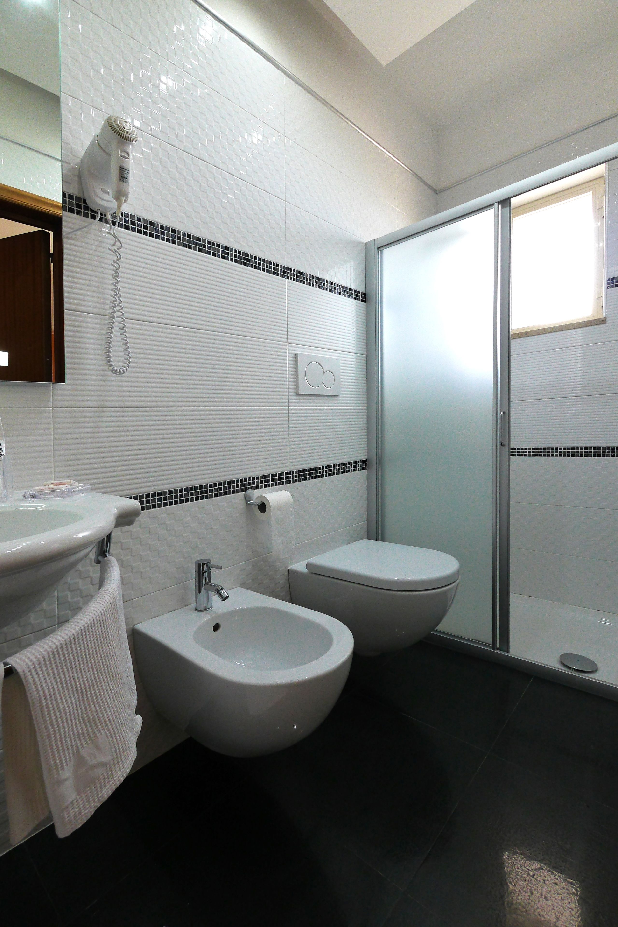 A bathroom with a sink, bidet, toilet, and a glass shower enclosure.