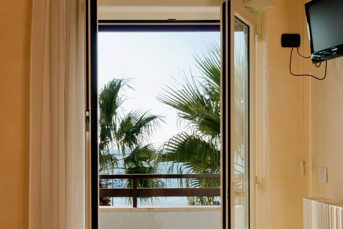 Une chambre avec un balcon, un lit, une chaise et une télévision.